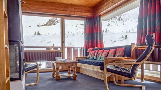Una habitación acogedora con sofá y sillones, una pequeña mesa y una chimenea.
