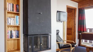 Una habitación acogedora con estantería, chimenea, televisor y mecedora.