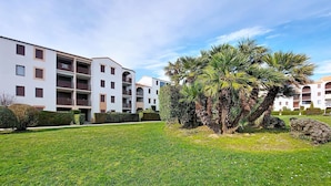 Un edificio residencial con varios balcones y un césped cuidado.