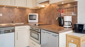Eine moderne Küche mit Edelstahlgeräten, einem Backofen, einer Spülmaschine und einer Kaffeemaschine.