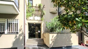 A building entrance with a glass door, steps leading up to it, and a small garden area with grass and a tree. - Caterina by Interhome (Sestri Levante)