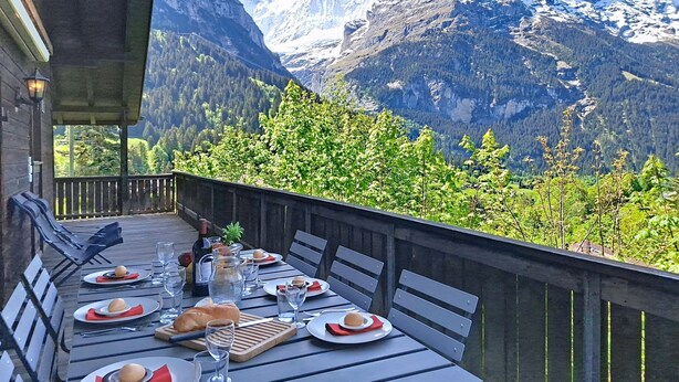 A dining table set outdoors with mountain views, wooden deck, and a mountain backdrop. - Egg-Isch by Interhome (Grindelwald)