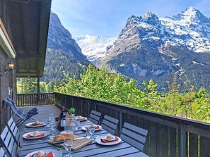 A dining table set outdoors with mountain views, wooden deck, and a mountain backdrop. - Egg-Isch by Interhome (Grindelwald)