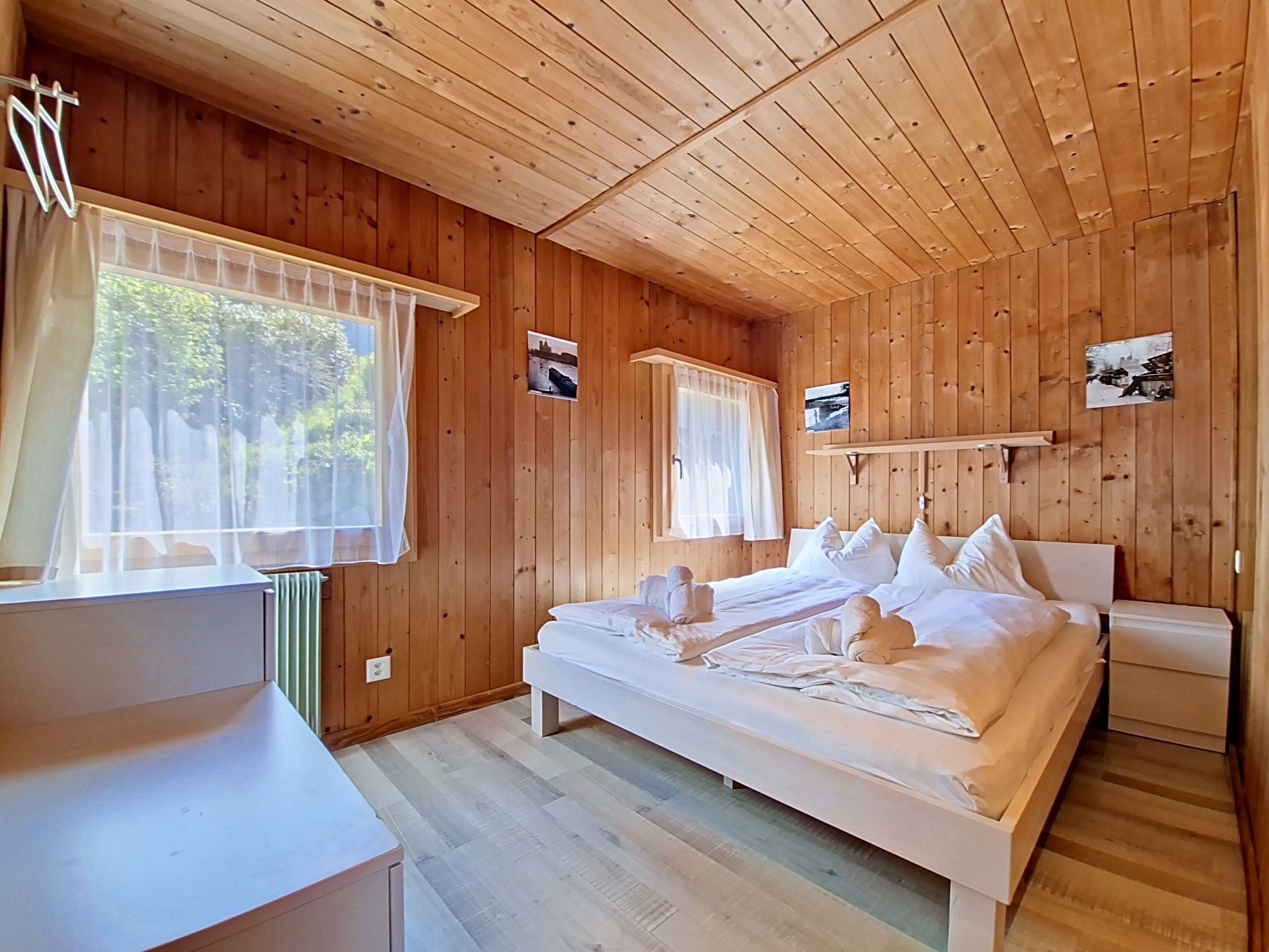 Une chambre à coucher dans une cabane en bois, avec un lit, des tables de chevet et une fenêtre avec des rideaux.