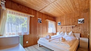 A wooden cabin bedroom with a bed, bedside tables, and a window with curtains. - Egg-Isch by Interhome (Grindelwald)