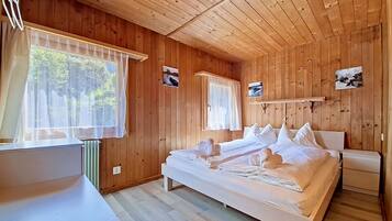 Une chambre à coucher dans une cabane en bois, avec un lit, des tables de chevet et une fenêtre avec des rideaux.