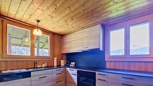 A modern kitchen with wooden cabinets, a built-in oven, and a large window. - Egg-Isch by Interhome (Grindelwald)