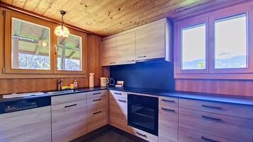 Une cuisine moderne avec des meubles en bois, un four encastré et une grande fenêtre.