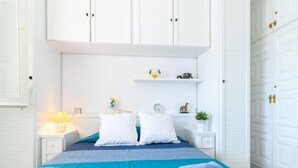 Une chambre d’hôtel bien rangée, avec un lit, deux tables de chevet, une petite table et une armoire.