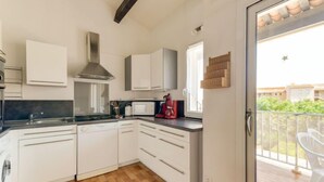 A modern kitchen with white cabinets, a stainless steel range hood, and a wooden floor. - Les Maldives by Interhome (Cap d'Agde)