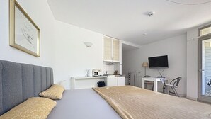 Una habitación de hotel con una cama, un escritorio, un televisor y una ventana.