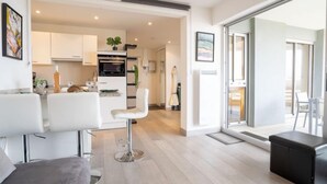 Un appartement moderne comprenant un coin repas, une cuisine et une grande porte-fenêtre coulissante donnant sur un balcon.