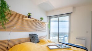 Une chambre à coucher moderne avec un lit, une table de chevet, une lampe et une fenêtre donnant sur un beau paysage.