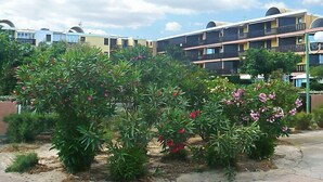 A residential building with multiple balconies, surrounded by lush greenery and flowering plants. - Gruissan Plage by Interhome (Gruissan)