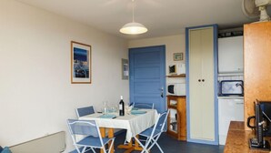 A compact room with a dining table, chairs, a small kitchenette, and a blue door. - Gruissan Plage by Interhome (Gruissan)