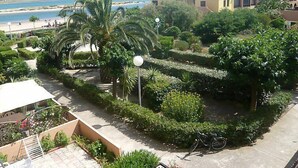 A landscaped garden with palm trees, a bicycle, and a view of the beach and ocean. - Gruissan Plage by Interhome (Gruissan)