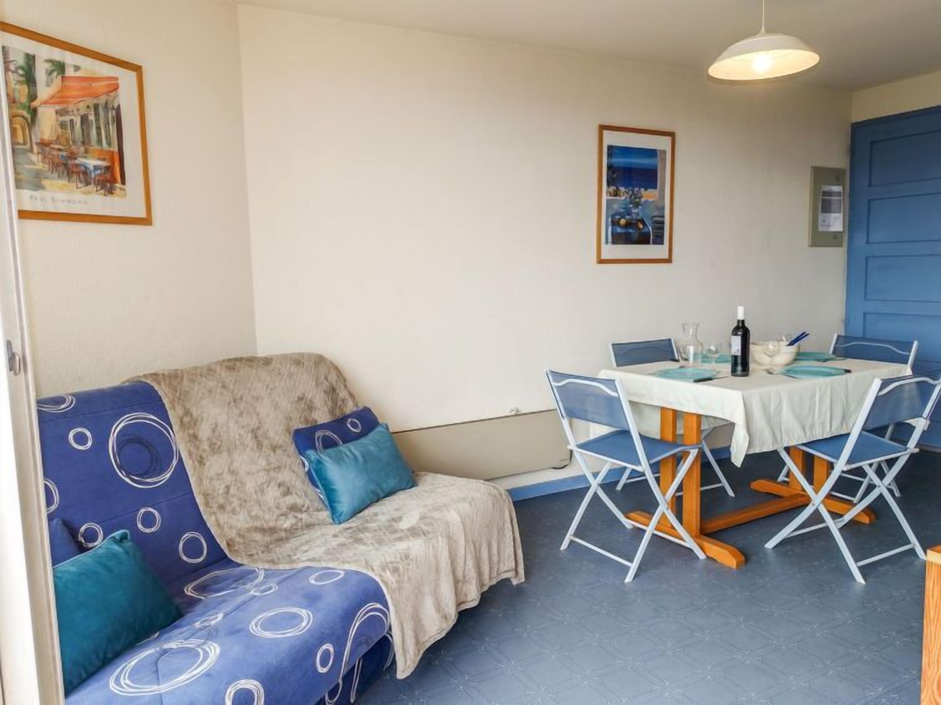 A cozy room with a sofa, a dining table with chairs, and a blue door.