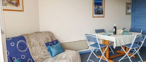 A cozy room with a sofa, a dining table with chairs, and a blue door.