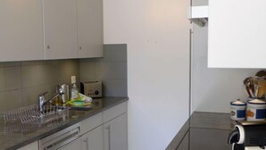 Eine moderne Küche mit grauen Schränken, einer Edelstahl-Spüle und einer Kaffeemaschine.