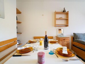 Une table à manger dressée avec des assiettes, des couverts, une bougie et une bouteille de vin.