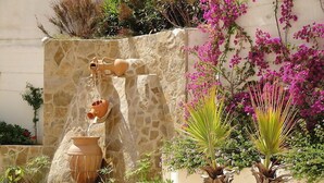 A garden with a water feature, including a stone wall and various plants. - Turquesa Beach 03 by Interhome (Calpe/Calp)