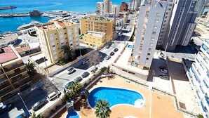 A coastal hotel with multiple high-rise buildings, a swimming pool, and a marina in the background. - Turquesa Beach 03 by Interhome (Calpe/Calp)
