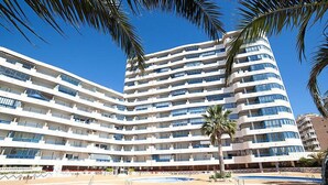 A multi-story hotel with a pool area, featuring a curved pool and palm trees. - Turquesa Beach 03 by Interhome (Calpe/Calp)