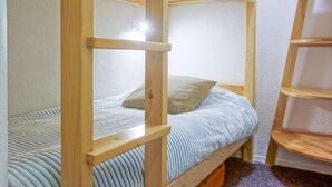 Ein Stockbett mit Holzgestell und einer Matratze mit Streifenmuster.