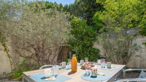 An outdoor dining area with a table set for four, surrounded by chairs.