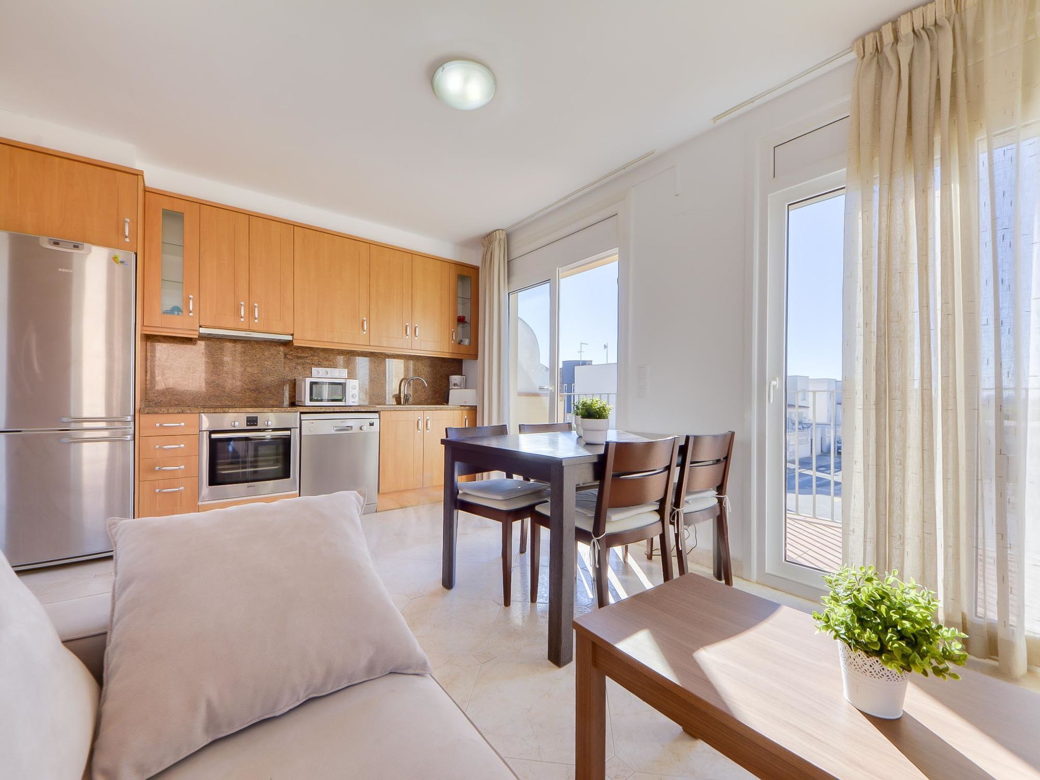 A modern kitchen with wooden cabinets, stainless steel appliances, and a dining area with a table and chairs.