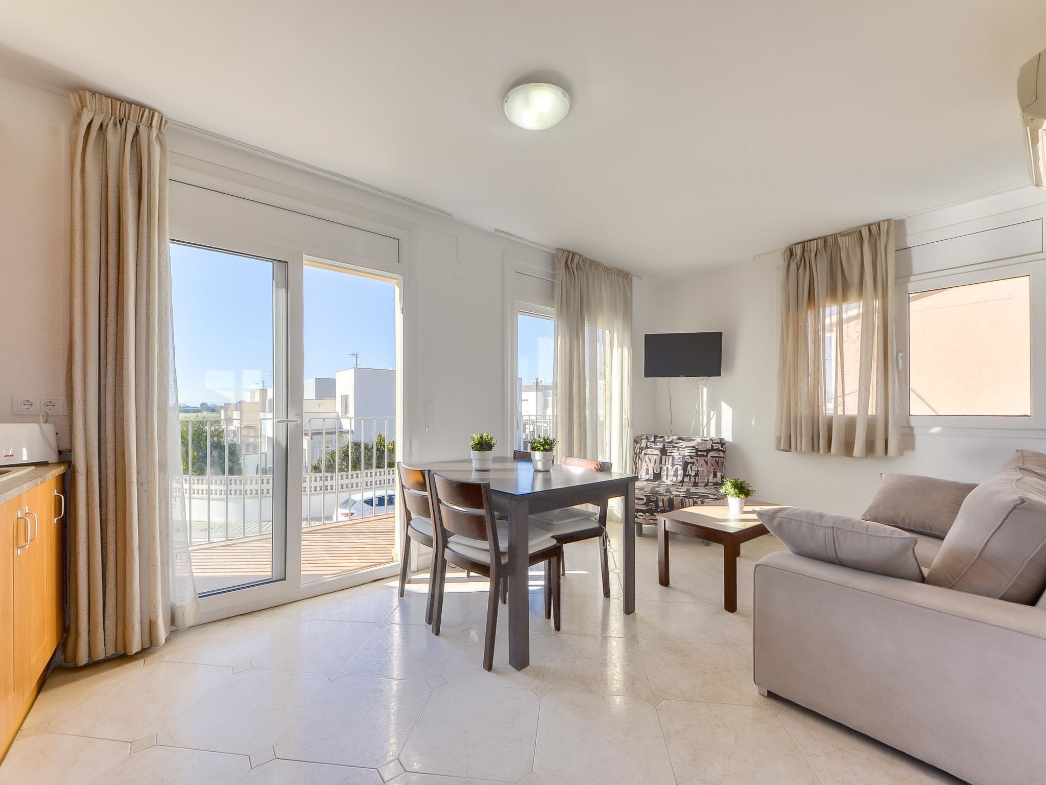 Um apartamento moderno com área de refeições, sofá e TV na parede.