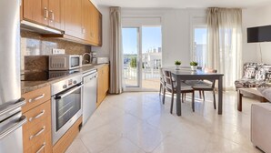 Una cucina moderna con mobili in legno, elettrodomestici in acciaio inossidabile e un'area pranzo con tavolo e sedie.