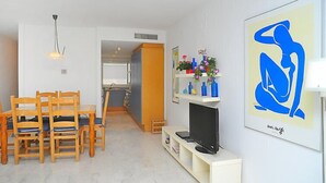 Un espace de vie compact comprenant un coin repas, une kitchenette et un téléviseur posé sur un meuble.
