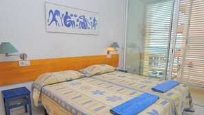 Une chambre d’hôtel avec un lit, une table de chevet, une lampe et une fenêtre avec des stores.