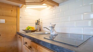 Uma cozinha com armários de madeira, bancada de granito, pia e uma estatueta decorativa de gato.