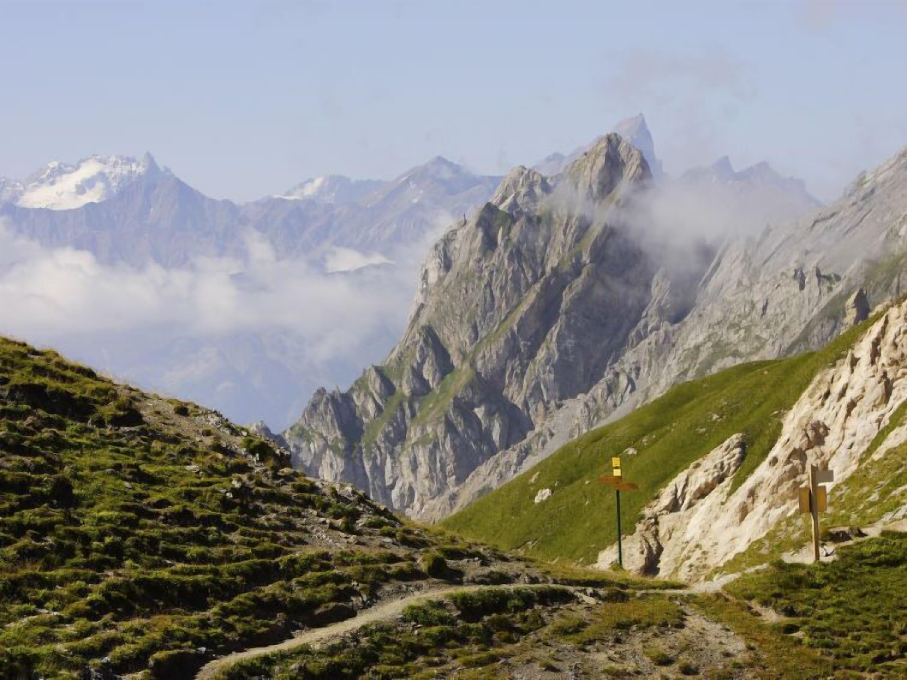 A mountain path with rocky terrain and sparse vegetation.