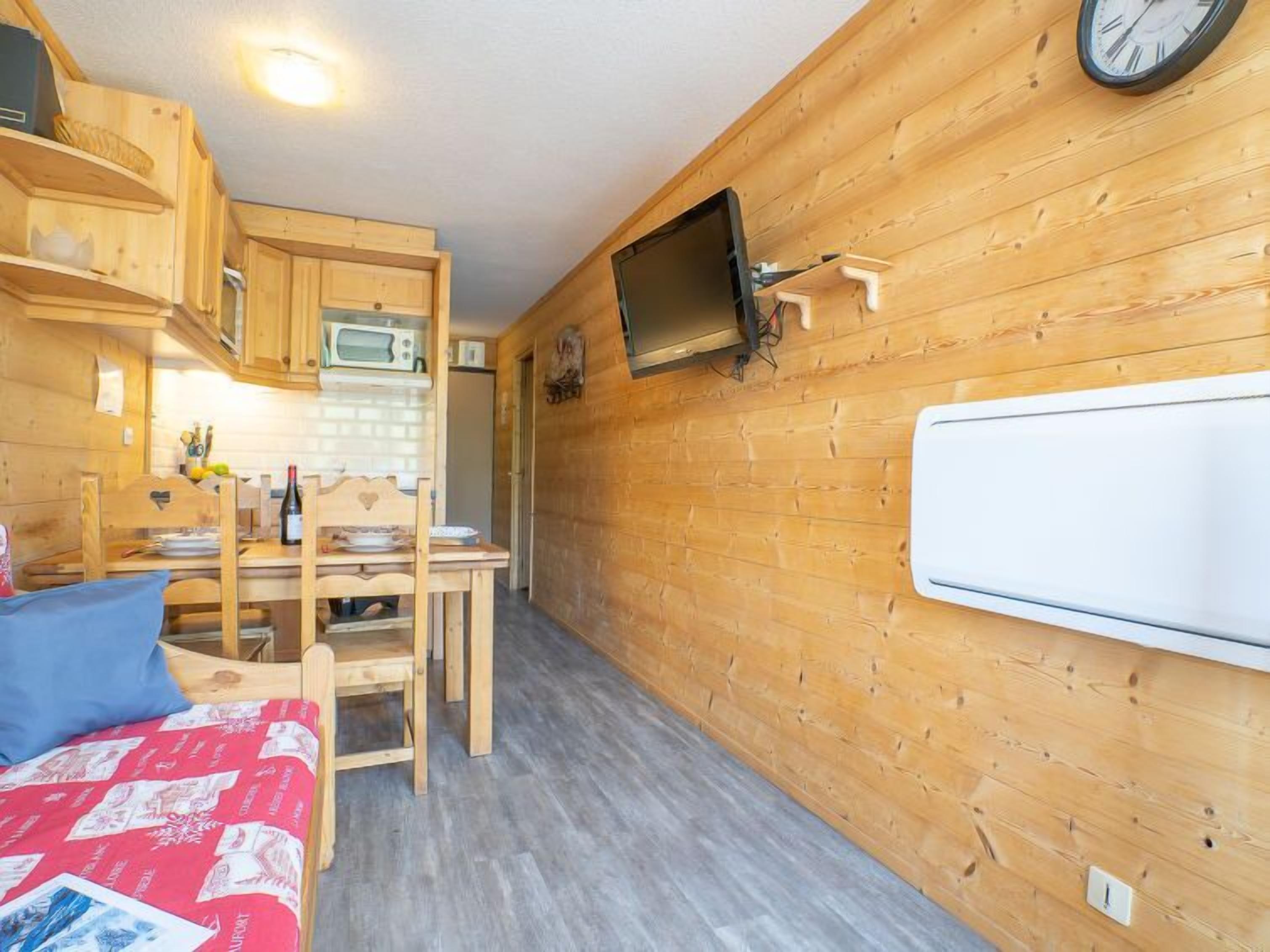 A compact, wooden interior with a kitchenette, a dining area, and a bed.