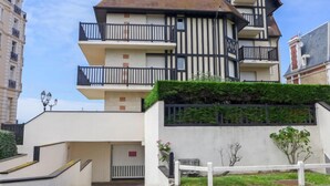 Un edificio a più piani con un mix di stili architettonici moderni e tradizionali, con balconi e un ingresso chiuso da cancello.