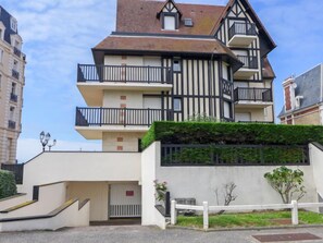 Un edificio de varios pisos con una combinación de estilos arquitectónicos modernos y tradicionales, con balcones y una entrada porticada.