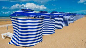 File di ombrelloni a righe su una spiaggia sabbiosa.