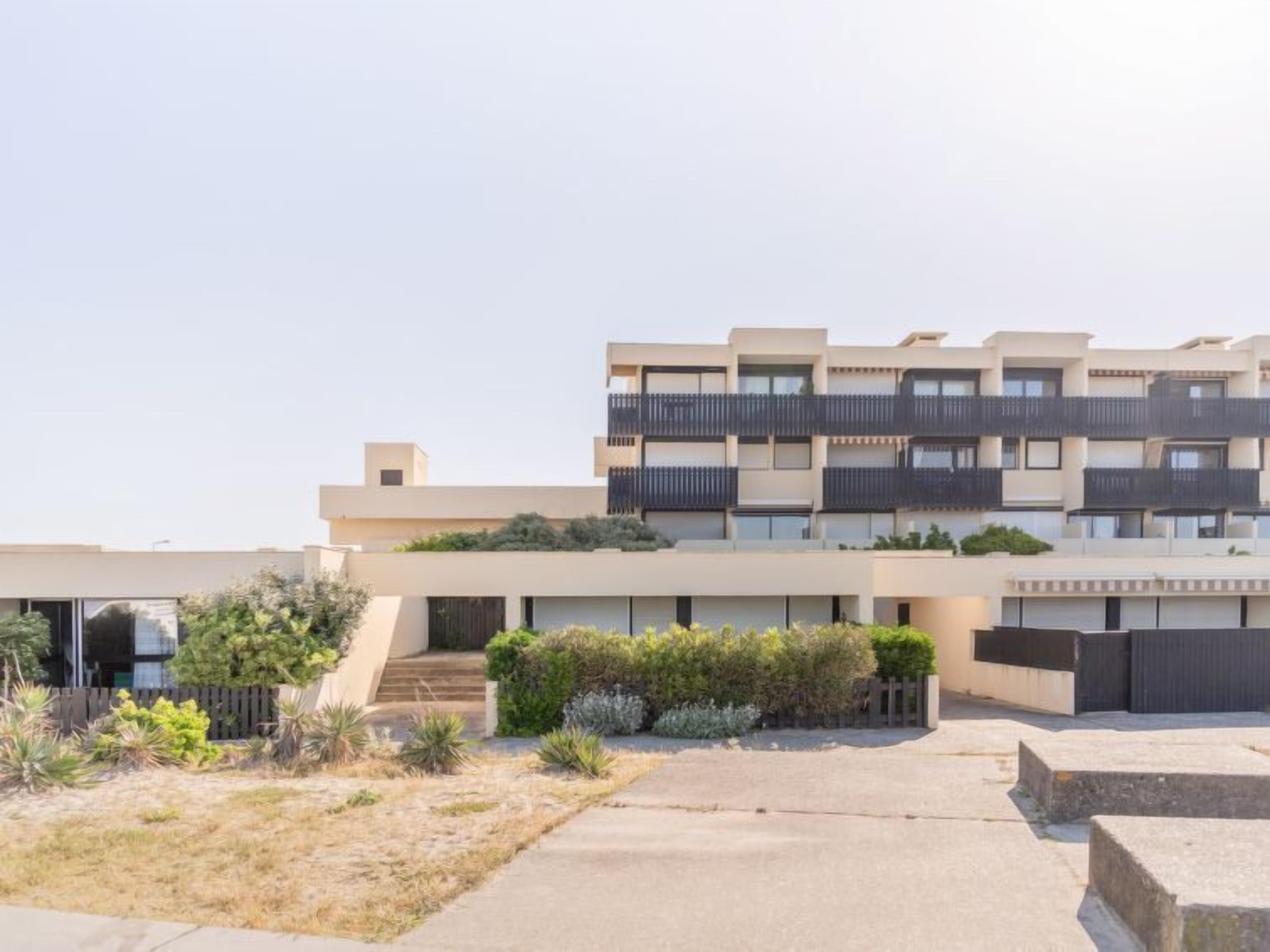 A modern multi-story residential building with balconies, a flat roof, and a landscaped courtyard.