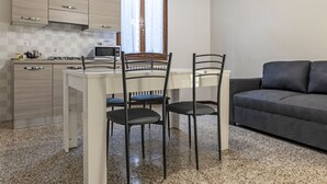 Un ambiente compatto con angolo cottura, zona pranzo e divano.