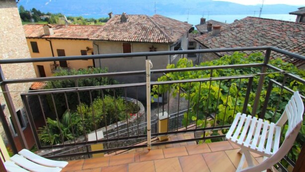Un balcone con vista su un paesaggio montuoso, un piccolo giardino e una sedia bianca.