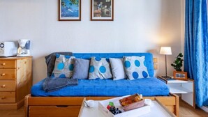 A cozy room with a blue sofa, wooden drawers, a coffee maker, and a tray with snacks. - Lunik Orion by Interhome (Le Corbier)