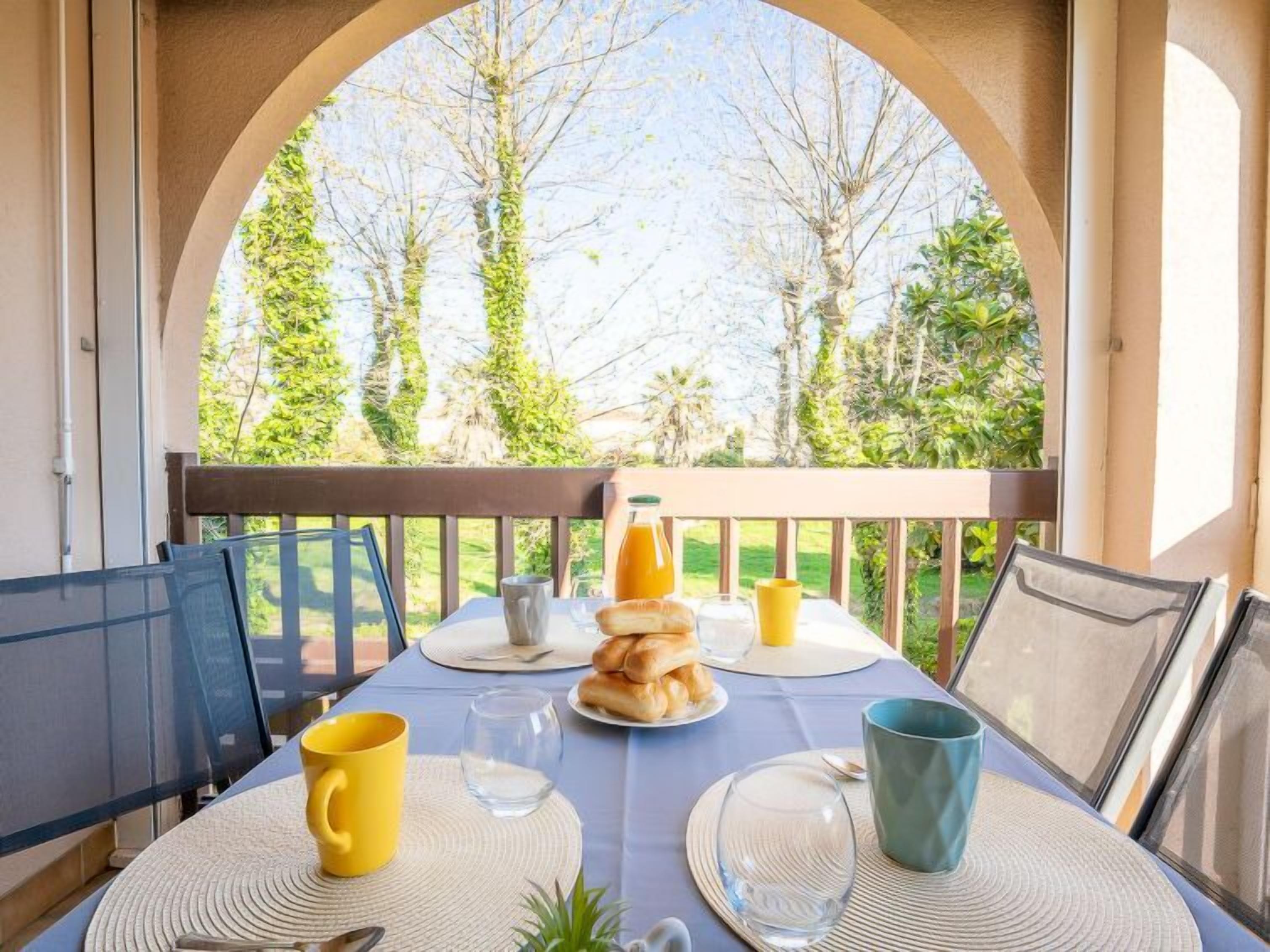 Una mesa de desayuno en un balcón con vistas a árboles y follaje.