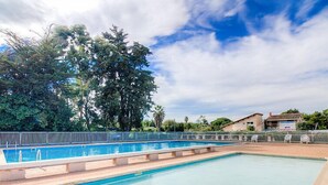 A rectangular swimming pool with a clear blue water surface, surrounded by a low stone wall and a metal fence. - Les Bastides de Grand Stade by Interhome (Saint Cyprien)