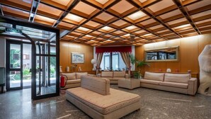 A lobby with a check-in desk, seating area, and a large window. - Universo by Interhome (Courmayeur)