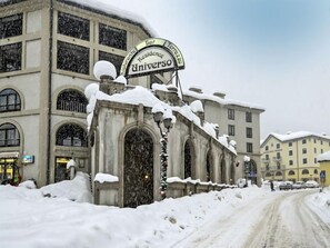 Un edificio coperto di neve con un cartello che riporta la scritta "Residence Universo Bar".