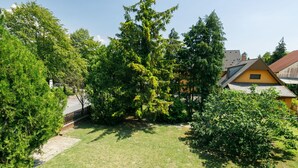 Un pati d'habitatge amb gespa, arbres i una casa groga.