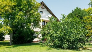 Una casa amb teulada inclinada, antena parabòlica visible i jardí ben cuidat.